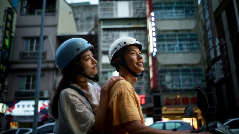 Jimmy and Ami wearing helmets on a scooter in the city in 18×2
