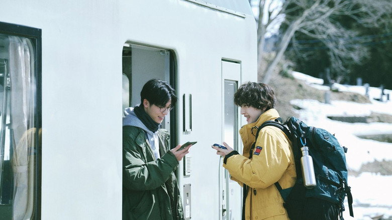 Jimmy and a new friend looking at their phones beside a train in 18×2
